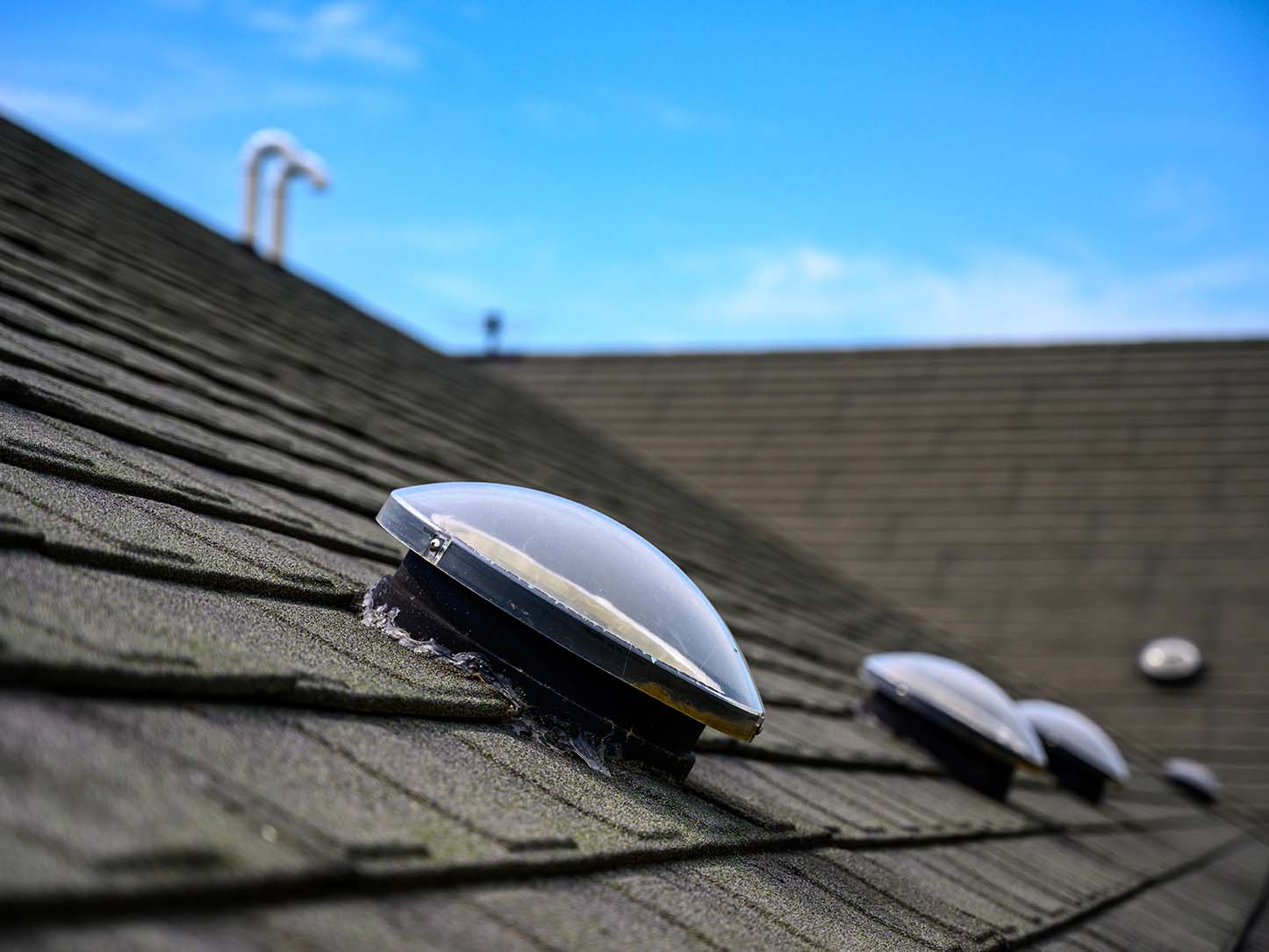 Dome shaped solar tube skylight on asphalt shingle roof